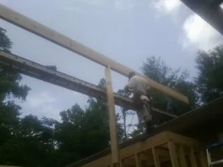 Carpenter setting a ridge beam over a new addition frame — Ice Dam Removal by Roofing Brothers in Elba