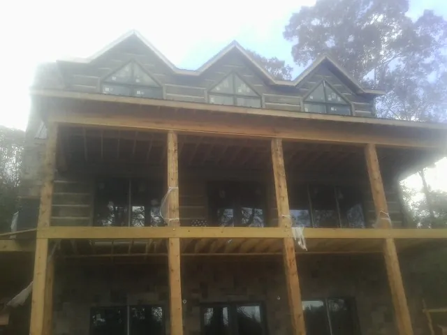 Dormers and porch framing on a large log home under construction — Roof Coating work by our crew in Elba