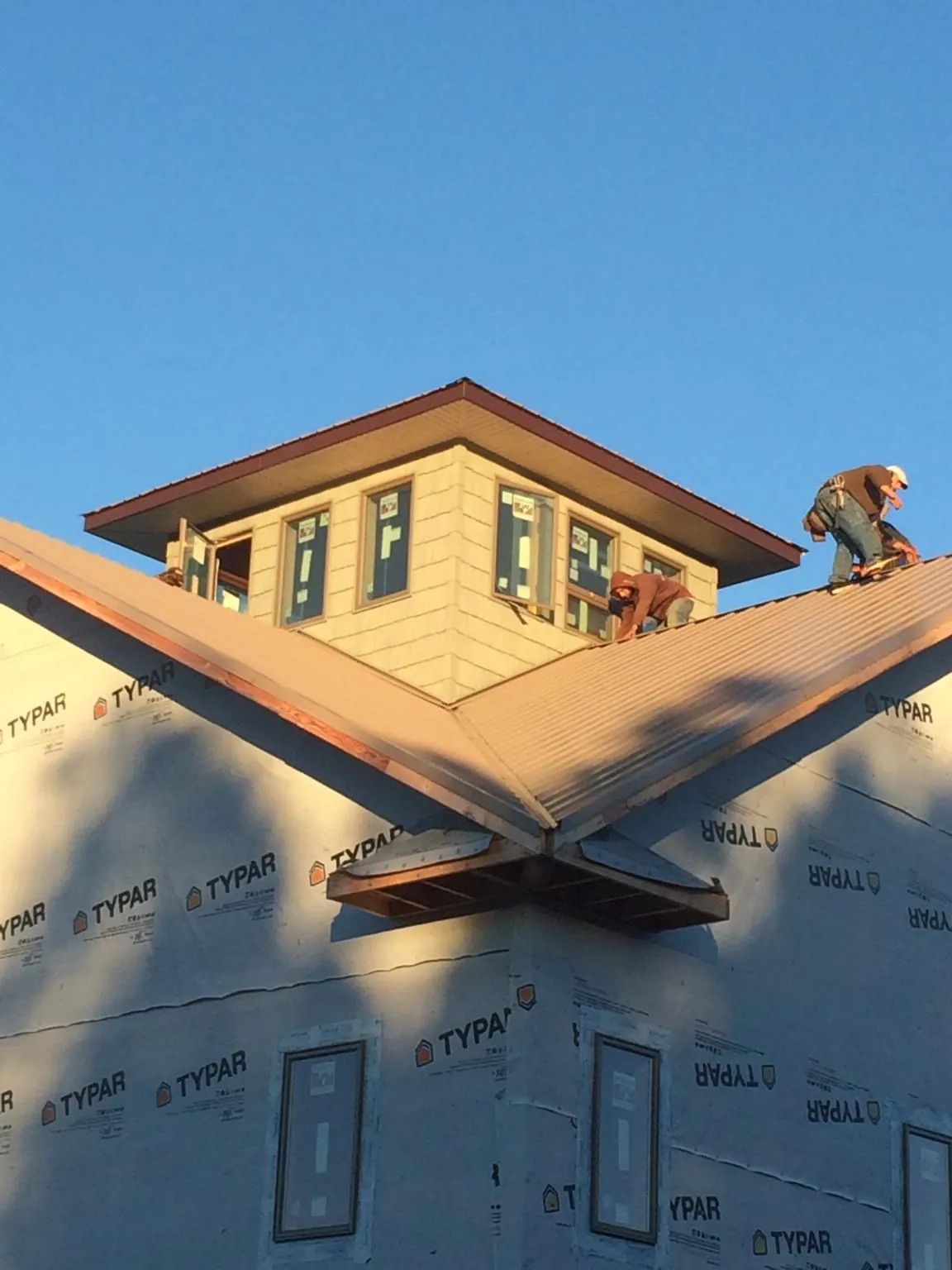 Roofers working around a rooftop cupola on a new metal roof at sunset — Roof Waterproofing in Elba by Roofing Brothers